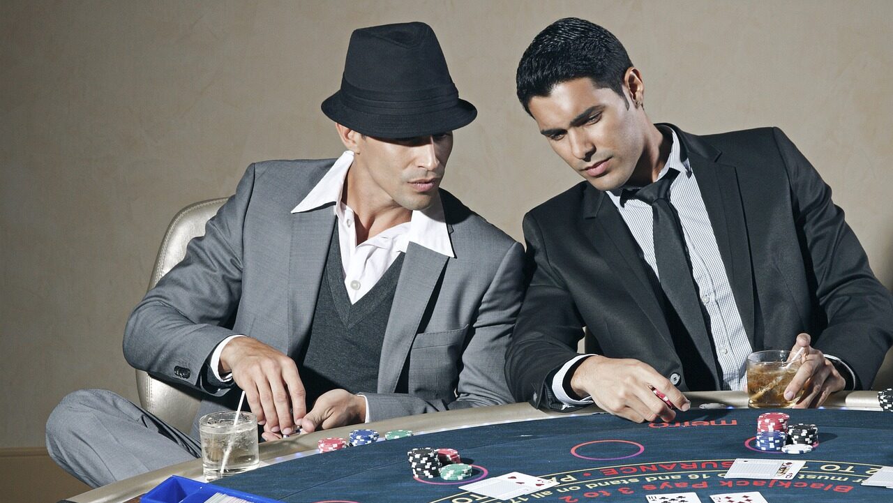 due giovani molto belli che scommettono a poker a un tavolo della roulette in un casinò vestiti in giacca e cravatta
